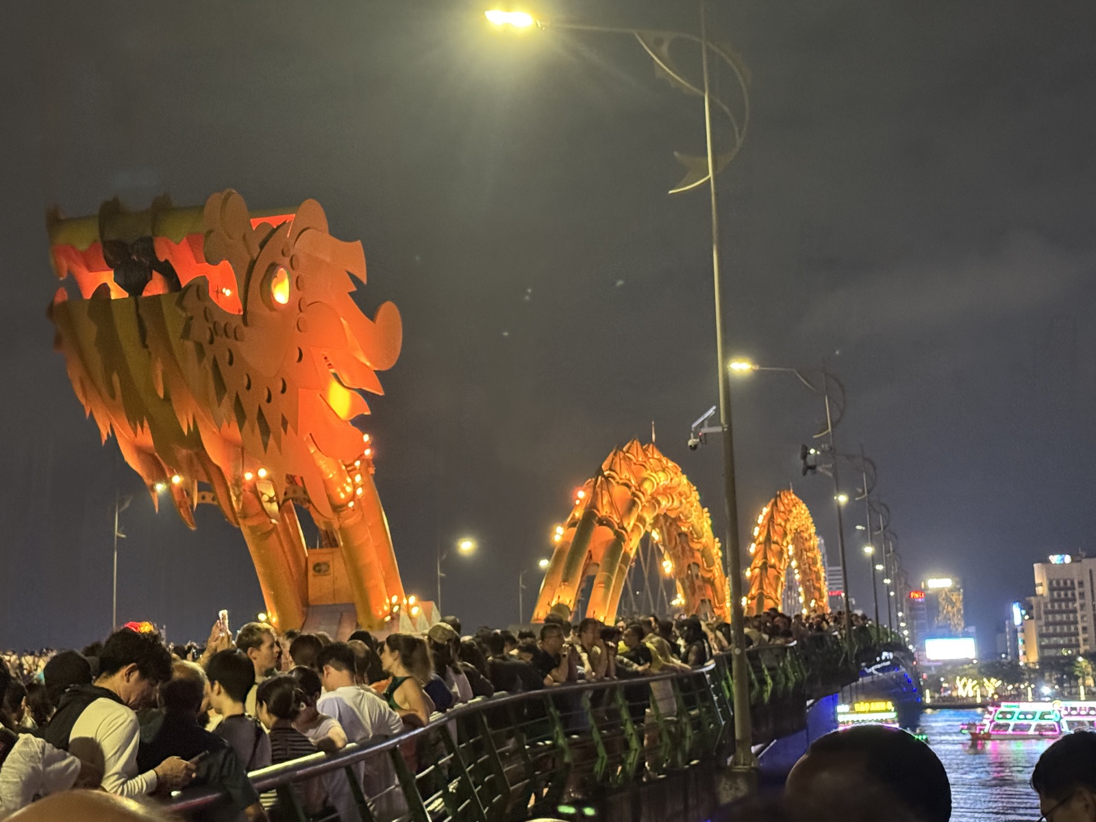 Dragon Bridge in Da Nang lit gold at night with crowds gathered for the fire show